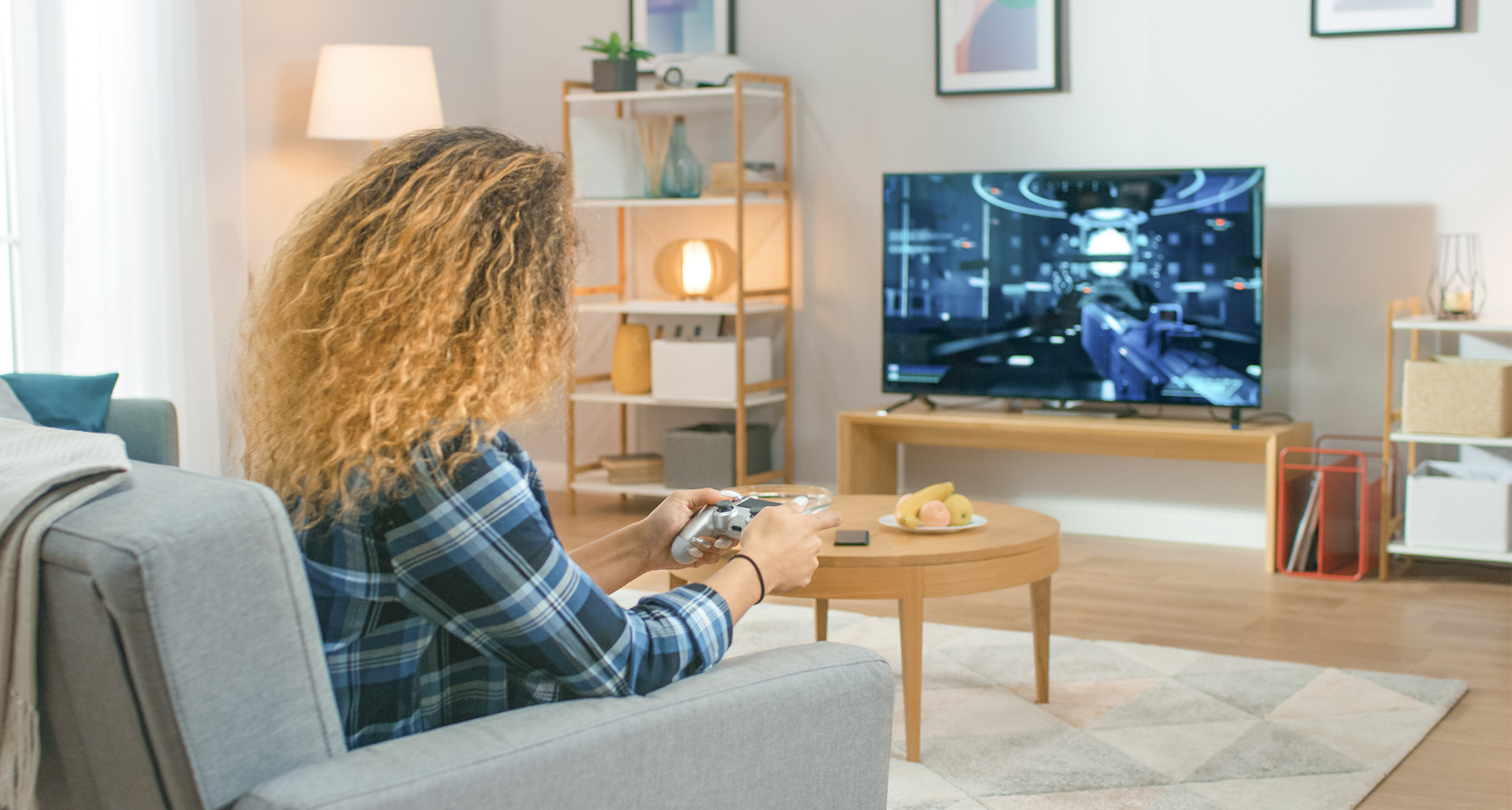 человек с длинными вьющимися волосами в гостиной играет в видеоигры на телевизоре